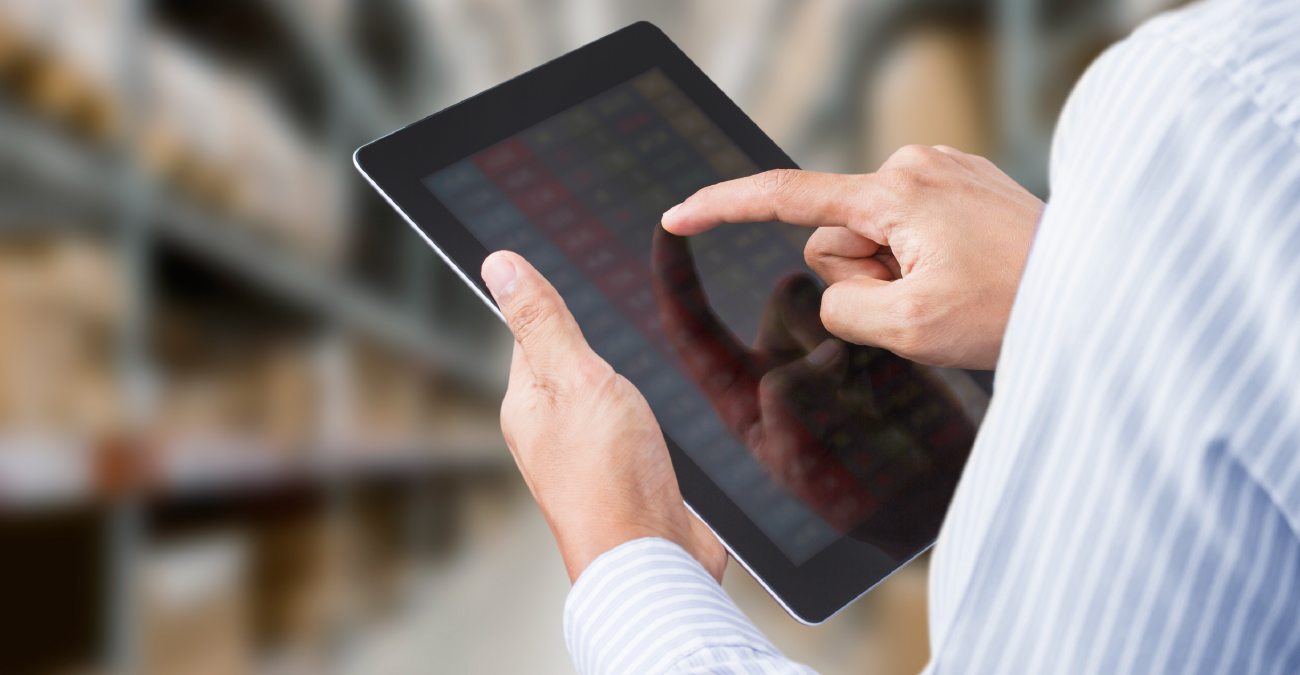 Businessman checking inventory in stock room on touchscreen tablet